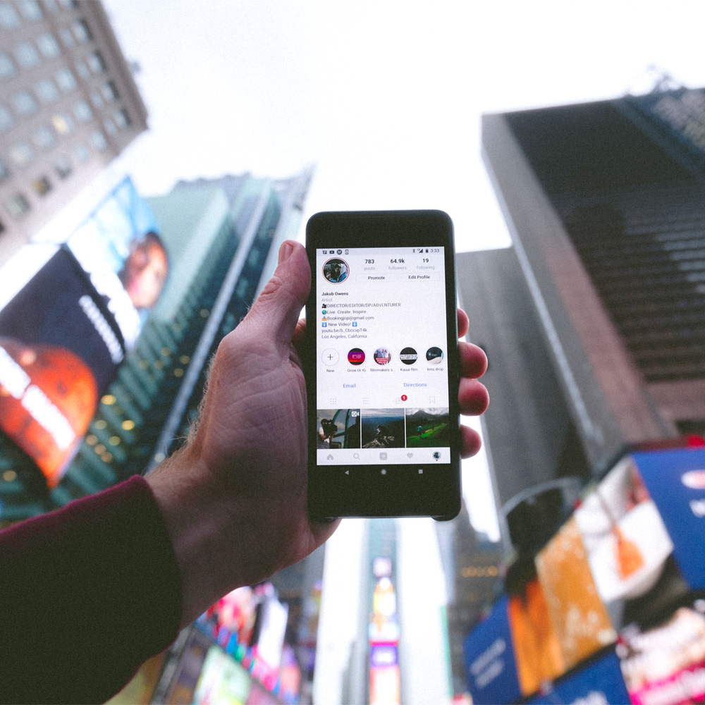 holding up phone next to buildings Photo by jakob owens on Unsplash